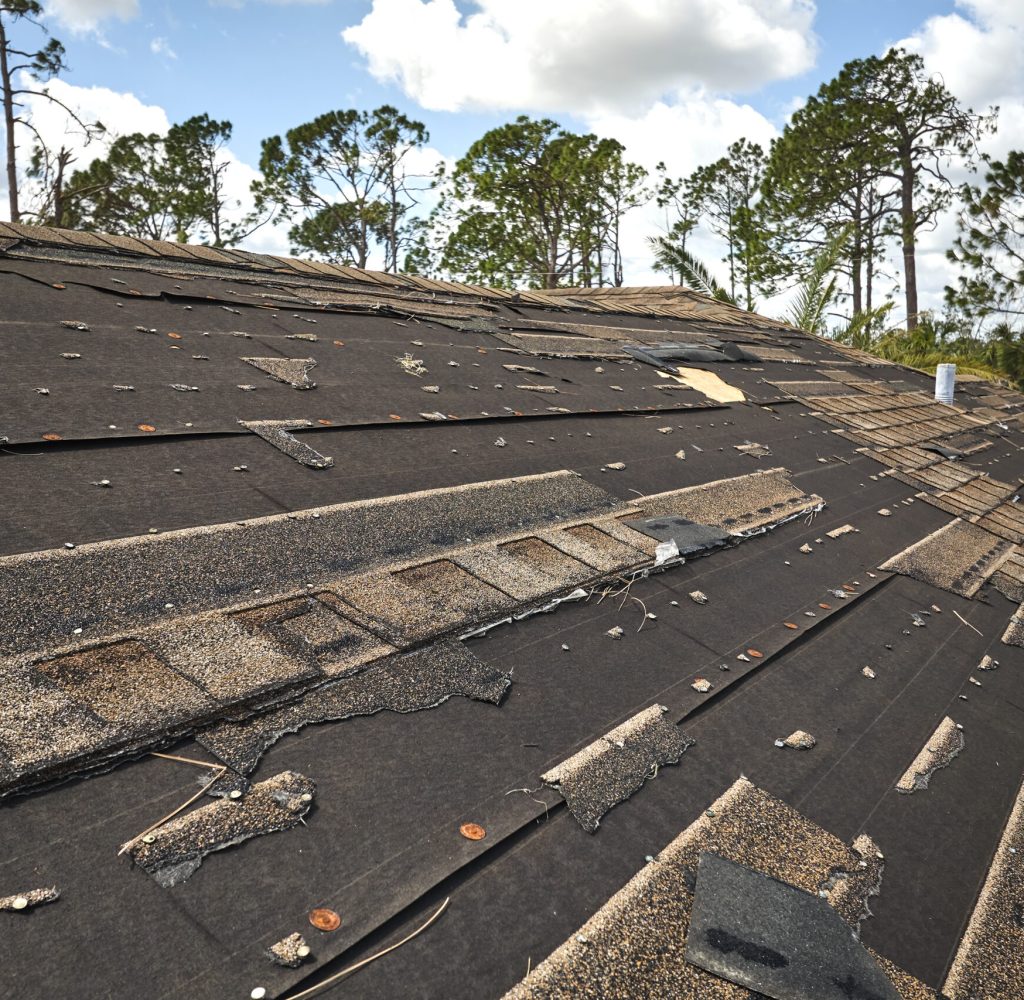 Damaged house roof with missing shingles after hurricane Ian in Florida. Consequences of natural disaster.